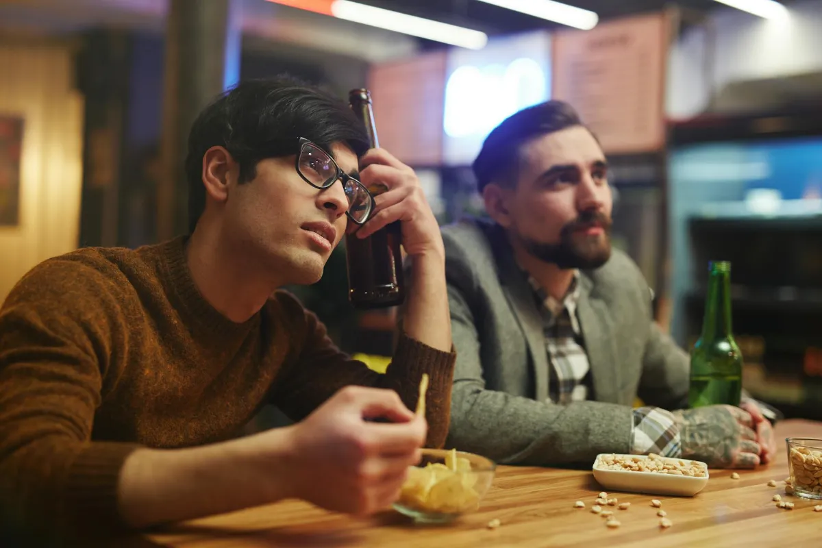 Aficionados al fútbol brindando con cervezas frente a una pantalla durante un partido del Mundial