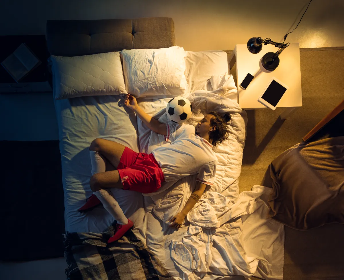 Aficionado estresado frente a televisor intentando dormir tras partido de fútbol del Mundial 2026