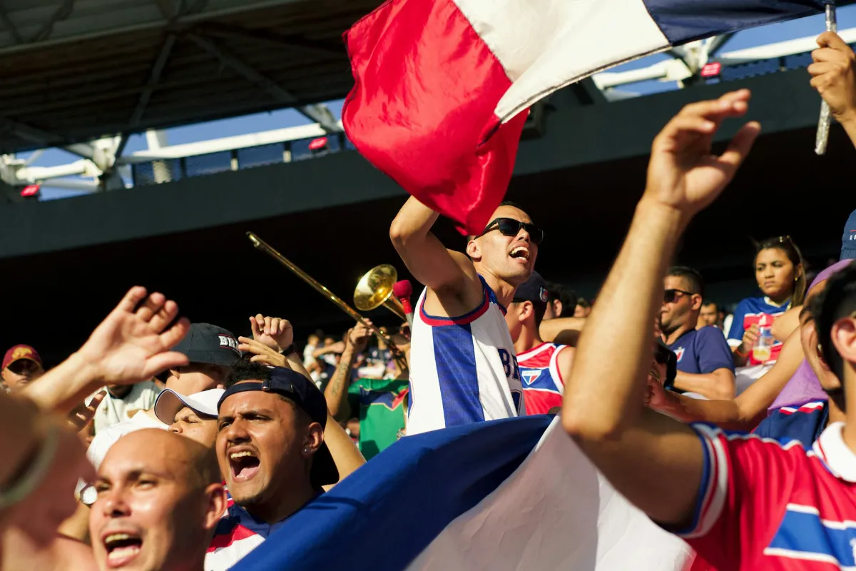 Hinchas de fútbol celebrando en el estadio representando la identidad grupal y el fanatismo extremo.