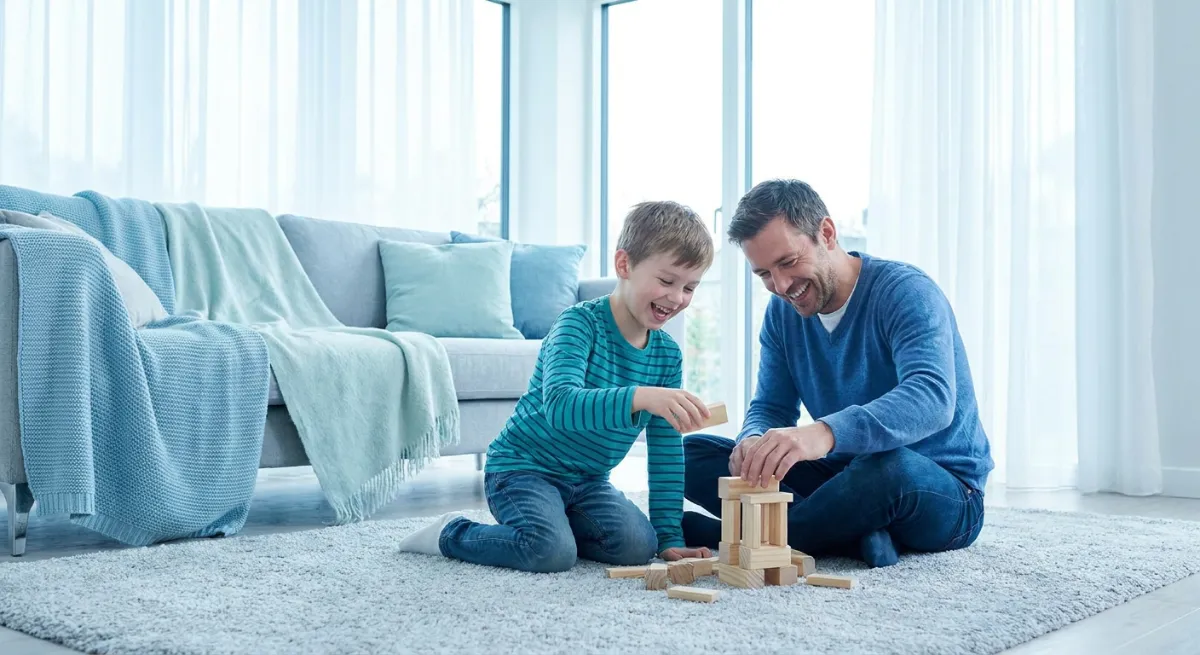 Padrastro y niño compartiendo un momento de juego y risas en un ambiente familiar acogedor.