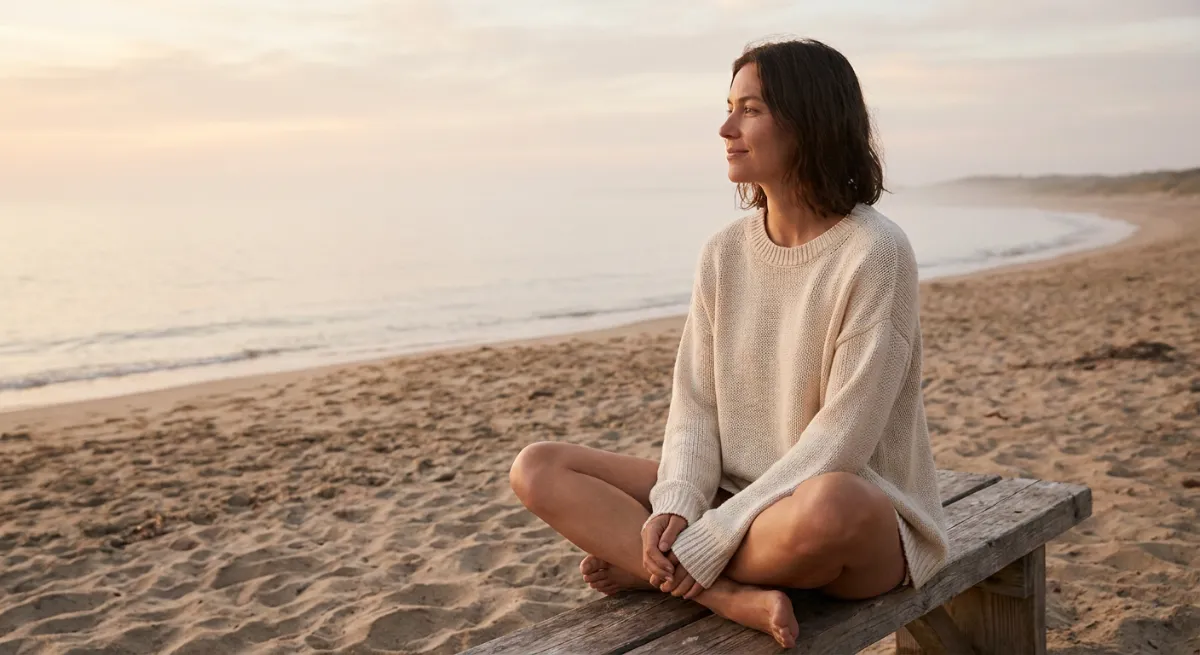 Persona sentada frente al mar en calma reflexionando sobre su proceso de sanación emocional tras una ruptura amorosa.