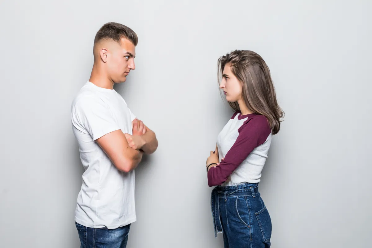 Pareja sentada en un sofá manteniendo una conversación seria y asertiva para resolver un conflicto emocional.